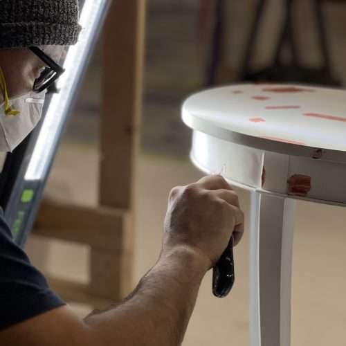 a man wearing a mask and gloves painting a table