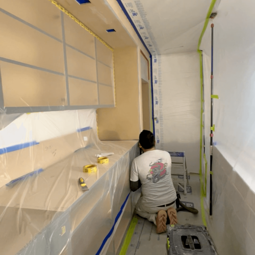 a man sitting on the floor in a room with plastic covering