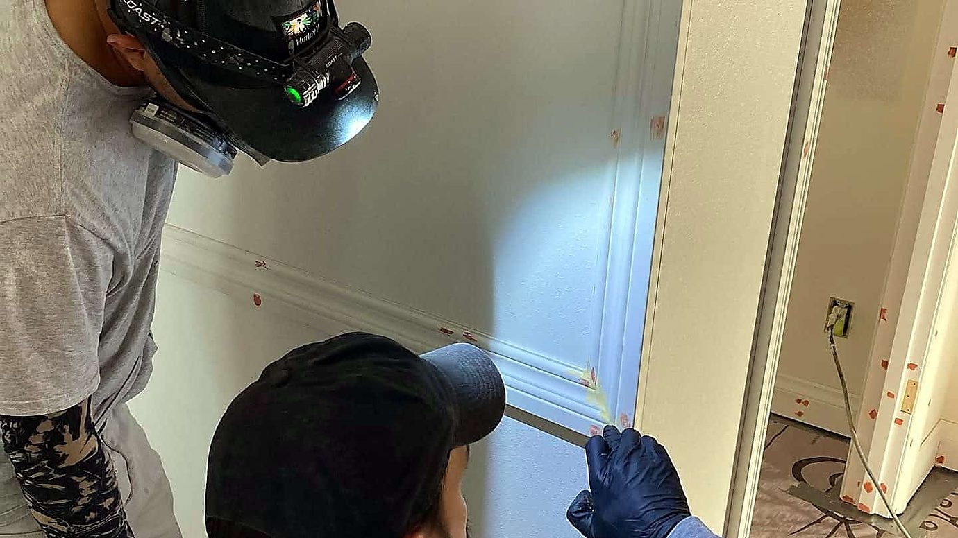 Two painters caulking trim joints before the finish coats