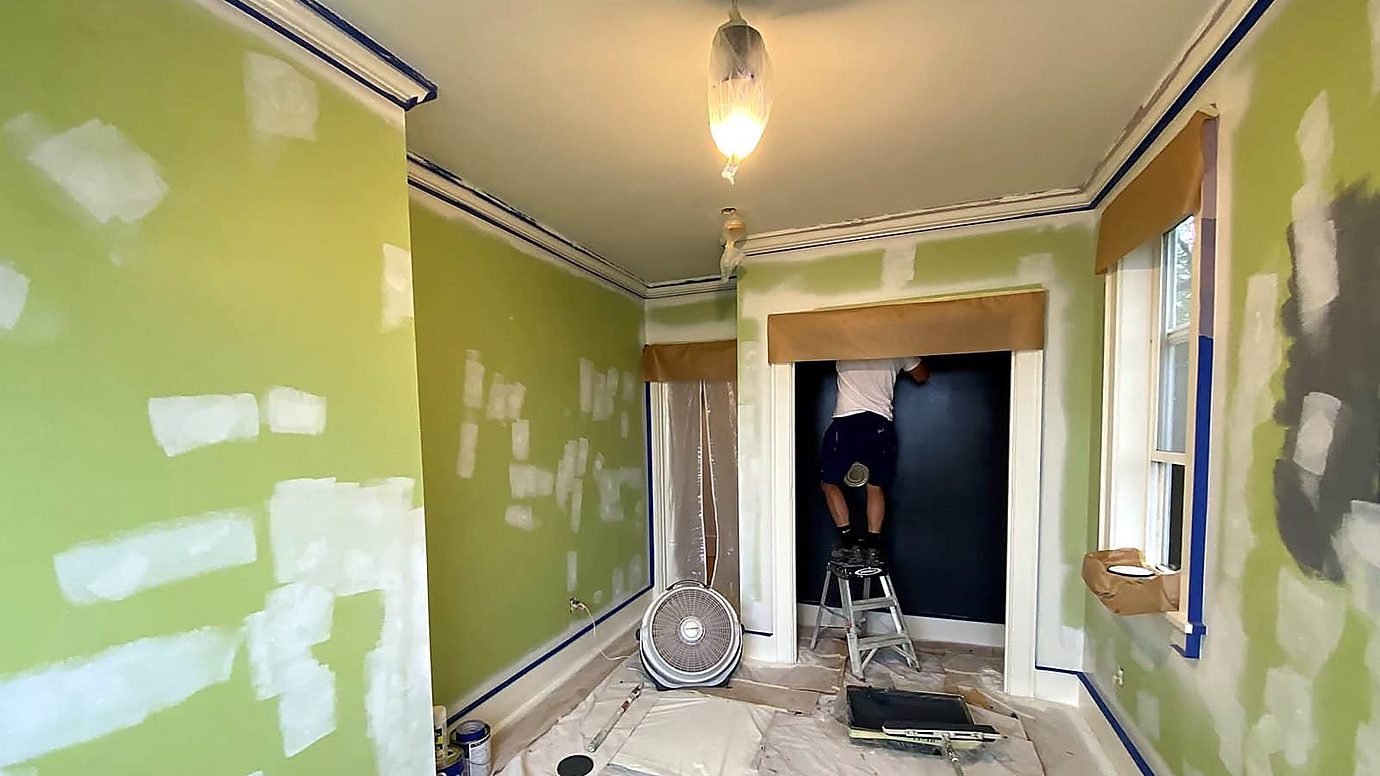 Room with floors covered, trim masked and drywall patches drying before painting