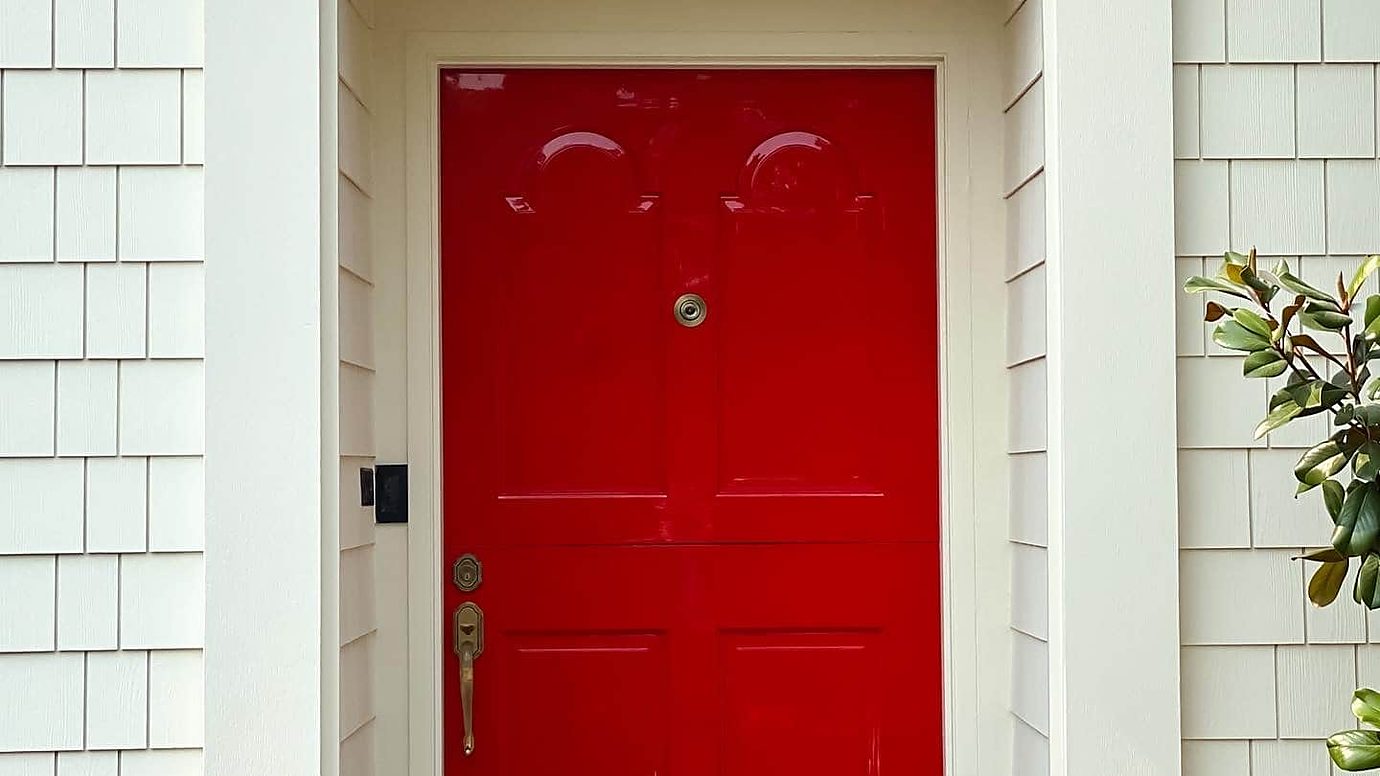 Red front door as an accent against white shingle siding